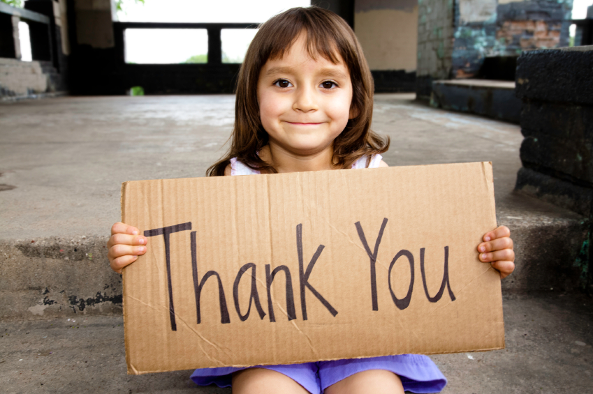 Little girl holding a cardboard sign that says thank you