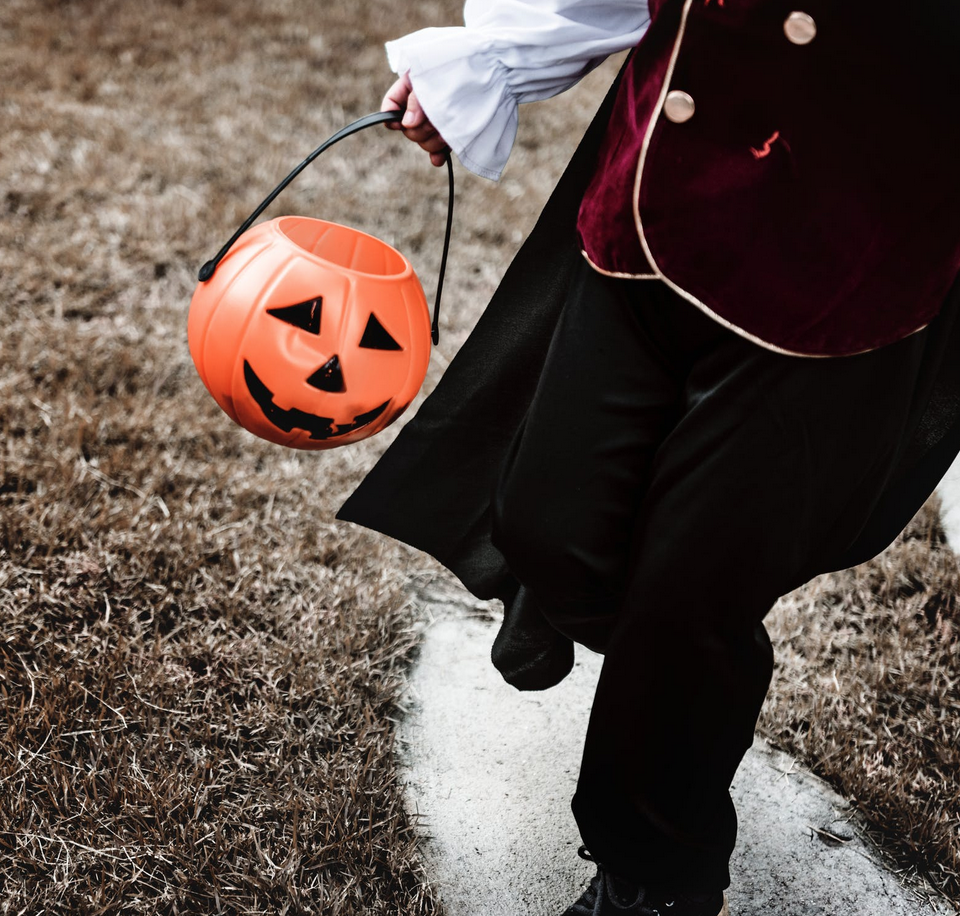Child holding a pumpkin halloween bucket